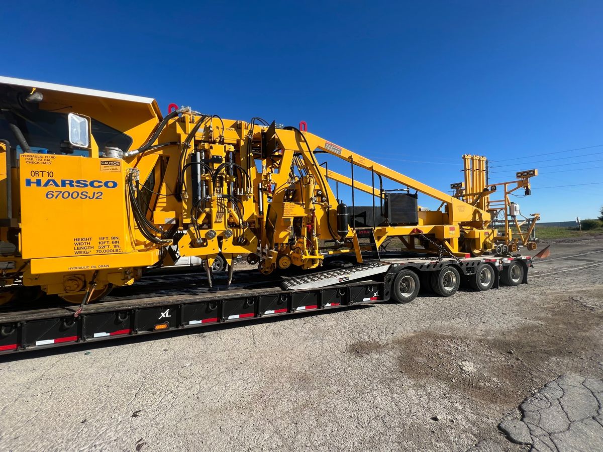 Rail maintenance machine loaded on a lowboy trailer